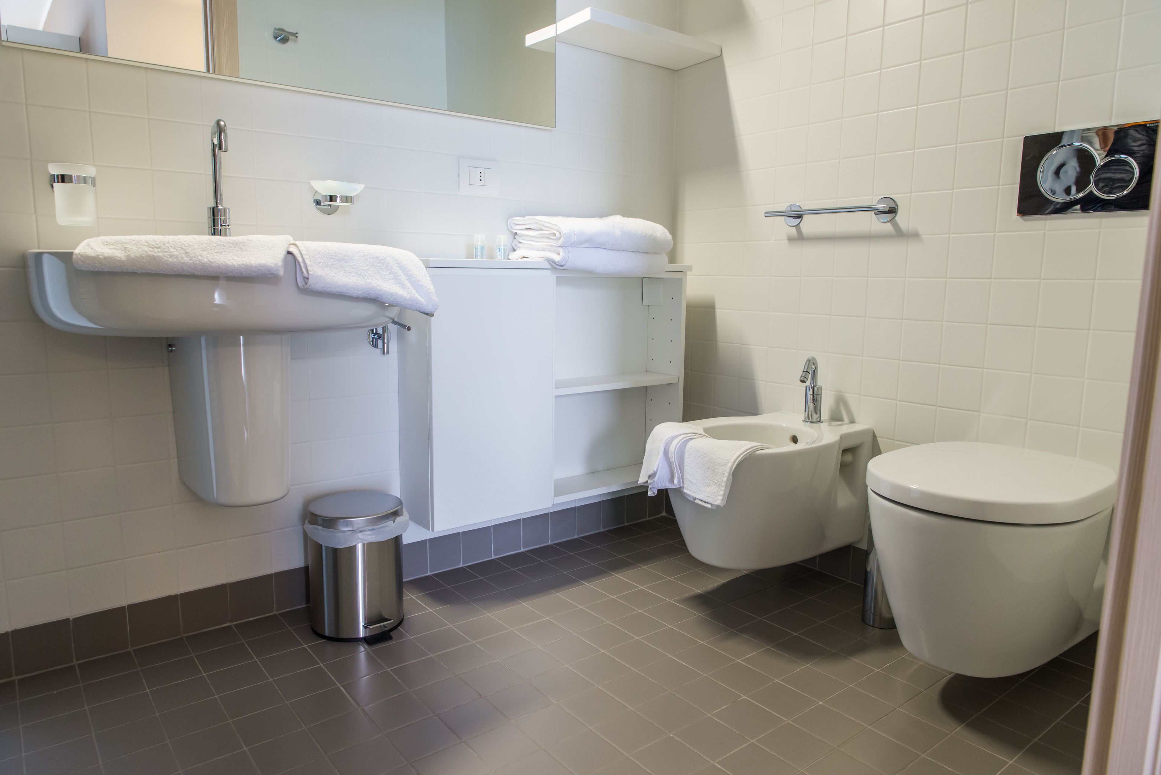 A modern bathroom with a sink, toilet, and bidet.