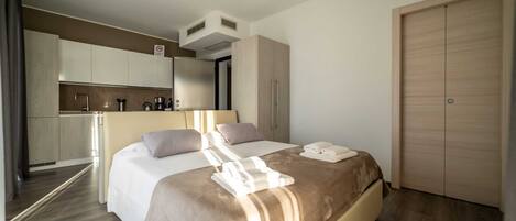 Een hotelkamer met een bed, een klein keukenhoekje, een kast en een badkamer.