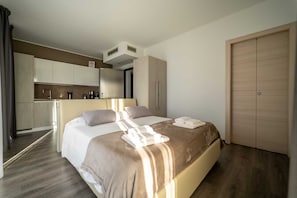 A hotel room with a bed, a small kitchenette, a wardrobe, and a bathroom. - Residenza Luigina (Perledo)
