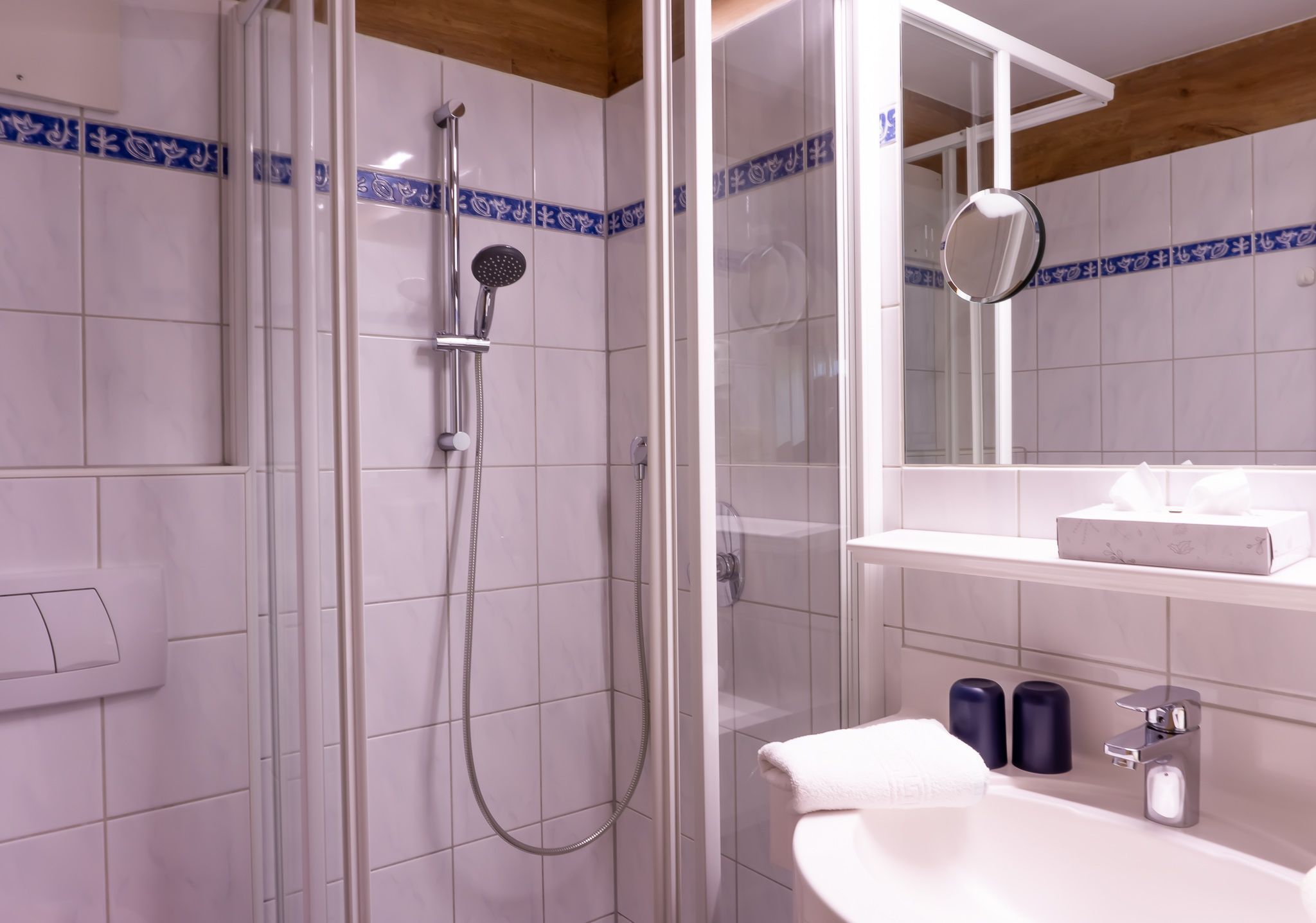 Une salle de bain avec une douche à parois de verre, un lavabo blanc et un miroir au-dessus du lavabo.