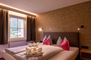 Une chambre d’hôtel avec un lit, une fenêtre avec des rideaux, une tête de lit et un mur orné d’un motif texturé.