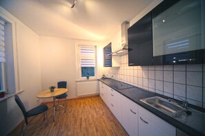 A compact kitchen with a dining area, a window with blinds, and a built-in stove.