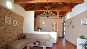 A living room with a wooden ceiling, a sofa, a coffee table, and a kitchen in the background. - Castello Domus (Mylopotamos)