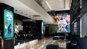 Un hall de hotel con mostrador de recepción, zona de estar y carteles grandes que promocionan 'The Wonderful World of Disney On Ice'.