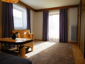 Une pièce avec une table en bois, une chaise, un vase de fleurs et un radiateur.