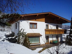 Un edificio de dos plantas con fachada blanca, balcones de madera y un paisaje cubierto de nieve.