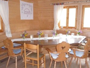 L’intérieur d’un chalet en bois est agrémenté d’une table de salle à manger ronde, de six chaises en bois et de centres de table floraux.