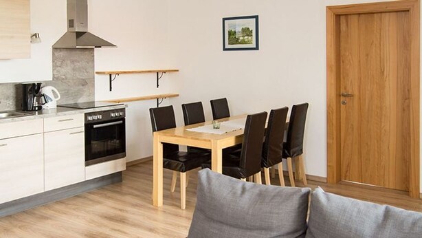 Una cocina moderna con una mesa de comedor y sillas, un sofá y una puerta de madera.