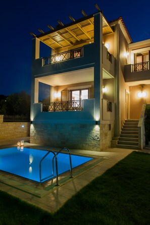 A two-story building with a swimming pool, outdoor lighting, and a staircase leading to the upper level. - Harmony of Nature villa (Rethymno)