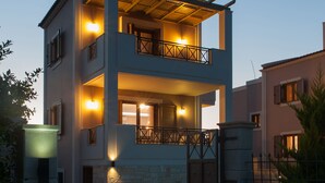 A modern two-story house with a balcony, a swimming pool, and a stone wall. - Harmony of Nature villa (Rethymno)
