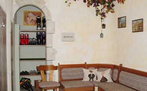 A cozy room with a wooden bench, a small table, and a shelf with various items. - Mezzanine No. 4 - apartment house Wöber (Tannheim)