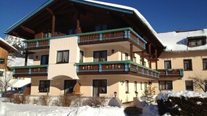 Un edificio de varios pisos con balcones, un techo cubierto de nieve y un cielo azul despejado.