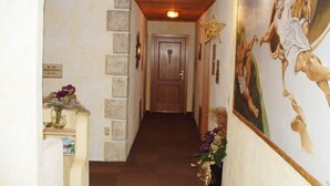 Un pasillo con techo de madera, pared de piedra, puerta de madera y un adorno de estrella en la pared.