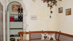 Una habitación acogedora con un banco de madera, una mesita y una estantería con diversos objetos.
