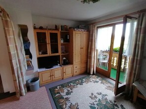 A room with a wooden cabinet, a small table, a trash bin, and a patterned rug.