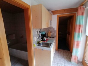 Una cocina compacta con armarios de madera, un lavamanos y una cafetera.