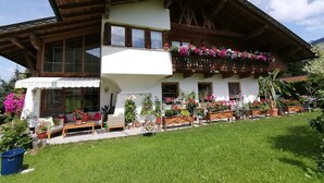 Xalet de dues plantes amb un balcó decorat amb flors, un porxo cobert i un jardí ben cuidat.