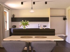 Eine moderne Küche mit Essbereich, einem schwarzen Sofa und einer Vase mit Blumen.