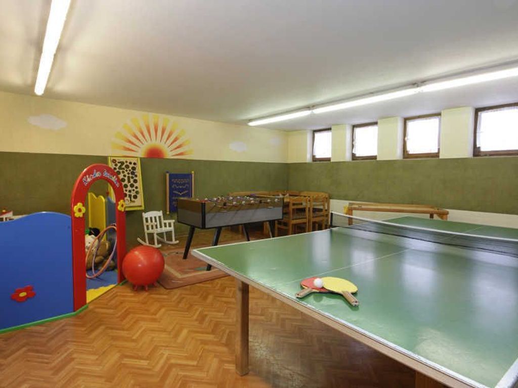 Une pièce équipée d’une table de ping-pong, d’un baby-foot et d’un espace de jeux avec une piscine à balles et une structure d’escalade.