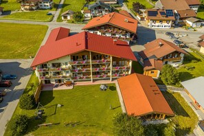 Ett hotell med flera våningar, balkonger, en parkeringsplats och en grön gräsmatta.