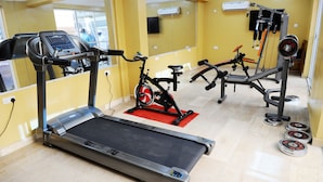 A gym with a treadmill, stationary bike, and weight equipment. - R&A City Hotel (Lagos)