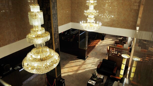 A lobby with a grand chandelier, a reception desk, and a seating area with sofas and a coffee table. - R&A City Hotel (Lagos)