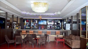 A bar area with a chandelier, bar stools, and a couch. - R&A City Hotel (Lagos)