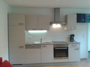 A compact kitchen with a built-in oven, a sink, and a stove.