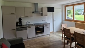 A compact kitchen with a built-in oven, a coffee maker, and a TV mounted above the oven. - Apartment Simone - Apartment Simone (Schoppernau)