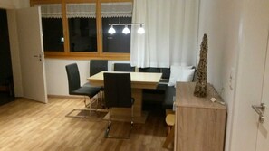 A dining area with a wooden table, black chairs, and a pendant light.