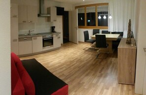 A compact living space with a kitchenette, dining area, and a red couch.