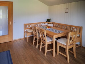 Puisesta ruokapöydästä on kuusi tuolia, lisäksi siinä on penkki ja seinällä pieni ruukkukasvi.