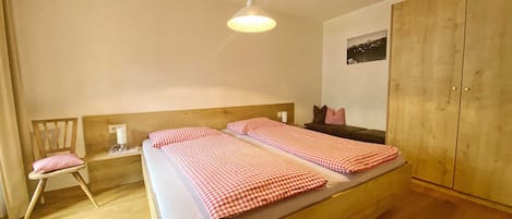 Un dormitorio con una cama grande, un armario de madera, una mesita de noche y una silla.