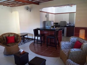 Un espacio habitable compacto con cocina, una mesa de comedor y dos sofás con cojines estampados.