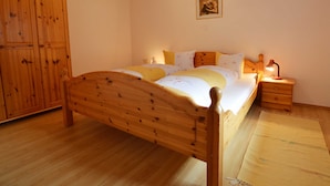 Un dormitorio con una cama de madera, una mesita de noche con lámpara, un armario y un cuadro enmarcado en la pared.
