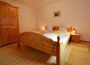 A bedroom with a wooden bed, a nightstand with a lamp, a wardrobe, and a framed picture on the wall. - Vacation apartment cat. 3 1 - Aktiv-Ferienwohnungen Pienz-Bobnar (Sautens)