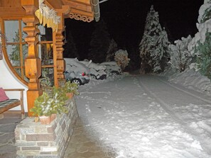 Un espacio exterior cubierto de nieve con una estructura de madera, un muro de piedra y un banco.