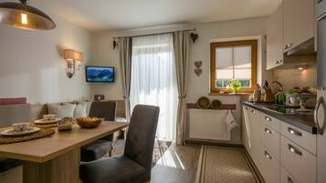 A modern kitchen with a dining area, a television, and a window with curtains.