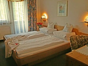 Una habitación de hotel con dos camas, una silla y dos lámparas de pared.