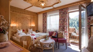 A wooden room with a bed, a table, a chair, and a television.