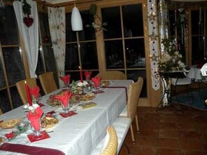 Un comedor con una mesa dispuesta para comer, sillas y una ventana con cortinas.