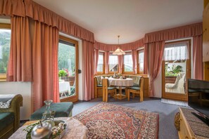 Una habitación acogedora con una mesa de comedor, sillas, televisión y una ventana con cortinas.