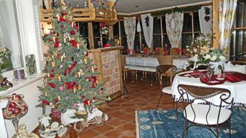 A dining area with a Christmas tree, a fireplace, and a table set for a meal.
