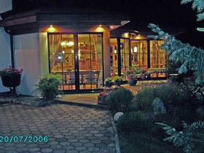 A building with a glass facade, a paved entrance area, and potted plants. - Vacation apartment Bergpanorama for 2 to 4 persons - Landhaus Dengg (Gerlos)
