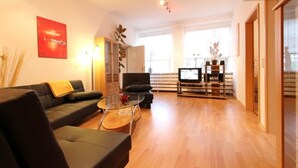 Una sala de estar moderna con un sofá, una mesa de centro de vidrio y una televisión.