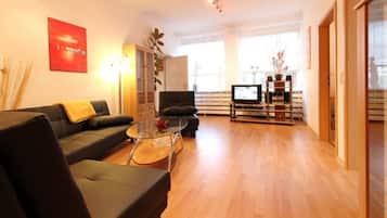 Ein modernes Wohnzimmer mit einer Couch, einem Glastisch und einem Fernseher.