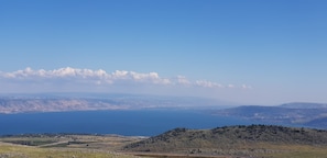 A coastal landscape with a clear sky, distant mountains, and a view of the sea. - Kami Suites Hotel  (Safed)