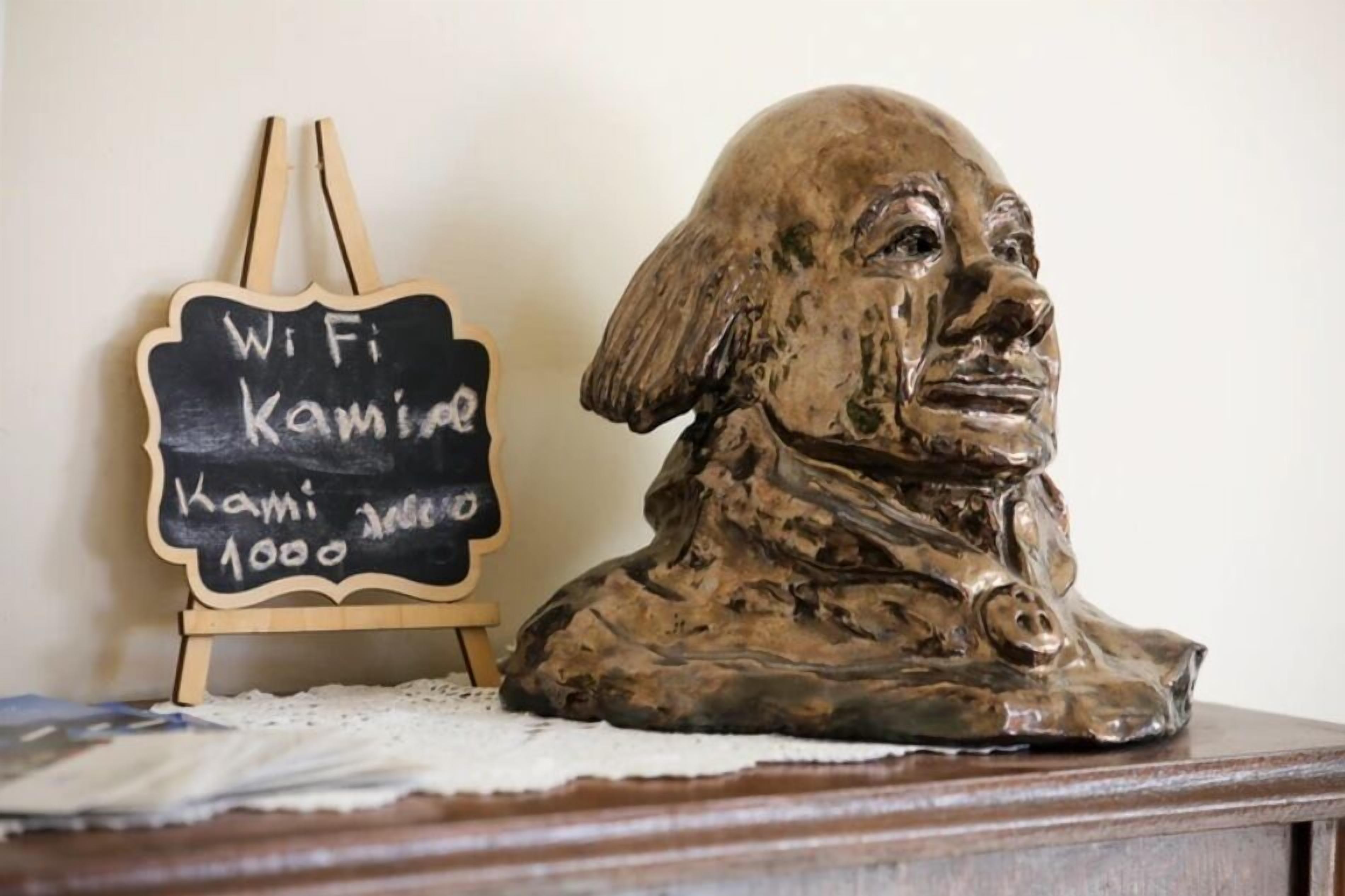 A bust sculpture on a wooden table with a chalkboard sign beside it.
