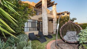 Una casa moderna con fachada de piedra, un balcón y un sillón colgante circular.