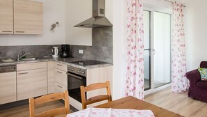 Una cocina con armarios de madera, una estufa y una mesa de comedor con mantel estampado.